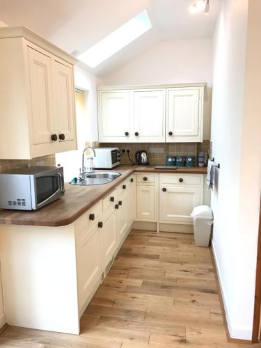 a kitchen with white cabinets and a sink at The Annex - Penzance town centre with parking in Penzance