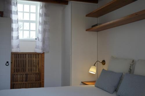 a bedroom with a white bed and a window at Canário do Mar - Rural Tourism in Angra do Heroísmo