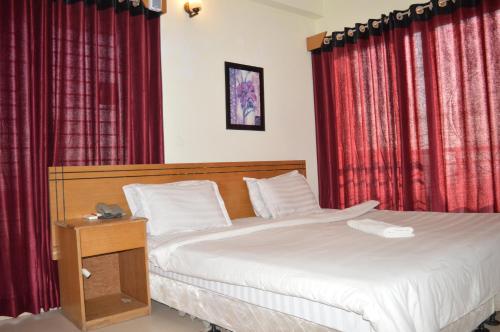 a bedroom with a bed with red drapes at Resort Islandia in Cox's Bazar