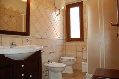 een badkamer met een wastafel, een toilet en een raam bij L'Agave in SantʼAntìoco