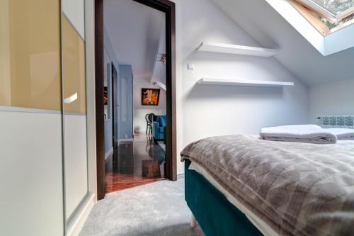 a attic bedroom with a bed and a glass door at Apartamenty Parkowa in Krynica Zdrój