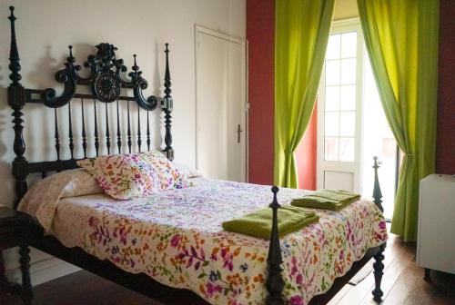 a bedroom with a bed with a wooden headboard and green curtains at Azores Dream Hostel in Ponta Delgada