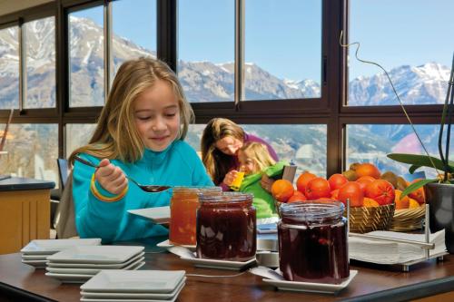een klein meisje aan een tafel eten bij VTF L'Ouka in Pra-Loup