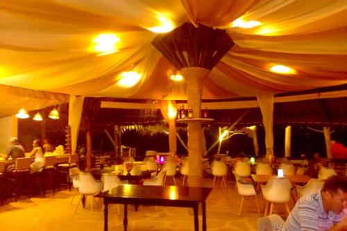 a man sitting in a restaurant with a tent at Bahari Dhow Beach Villas in Diani Beach