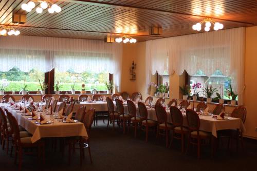 una sala de banquetes con mesas y sillas y una habitación con ventanas en Hotel zum Nordpol en Schenefeld