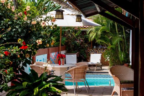 a patio with chairs and an umbrella and a pool at Pousada Le Baron in Praia do Frances