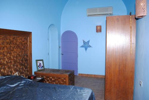 a bedroom with a bed and a blue wall at Nubian Holiday House Aswan in Aswan