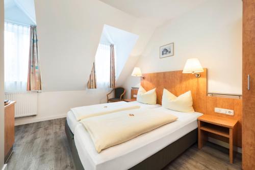 a bedroom with a large white bed with a wooden headboard at Am Klostergarten in Freising