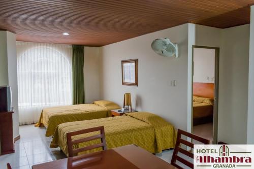 グラナダにあるHotel Alhambraのベッド2台とテーブルが備わるホテルルームです。