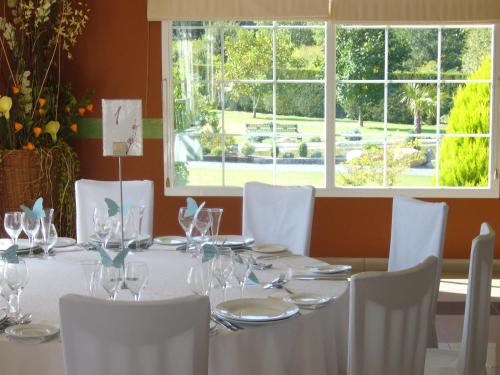 a dining table with white chairs and a large window at Hotel Restaurante La Alhama in Medina de Pomar