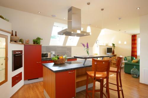 a kitchen with red cabinets and a counter with chairs at Komfort Appartements Zirbenland - adults only - no dogs in Weißkirchen in Steiermark