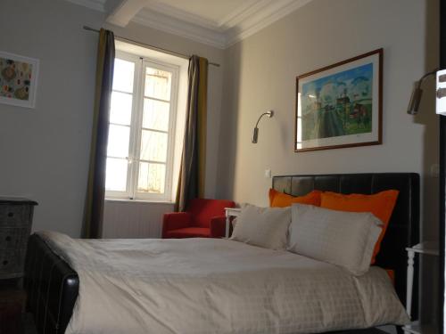 une chambre avec un lit et une chaise rouge dans l'établissement Clos du Magnolia, à Causses-et-Veyran