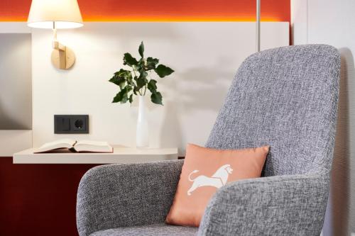 a grey chair with a pillow with a dog on it at Best Western Hotel Leipzig City Centre in Leipzig