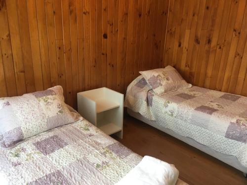 two beds in a room with wooden walls at Casa Florecer in Contulmo