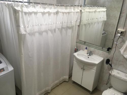 a bathroom with a white shower curtain and a sink at Casa Florecer in Contulmo