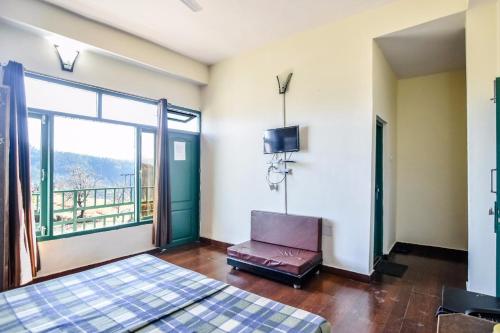 a room with two beds and a television and a balcony at Trimurti Pine Valley Resort in Shimla