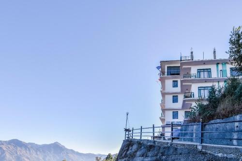 a building on the side of a mountain at Trimurti Pine Valley Resort in Shimla