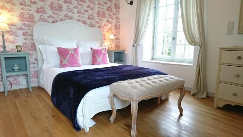L'Olivier في Monts-sur-Guesnes: غرفة نوم بسرير ابيض وبطانية زرقاء ومقعد