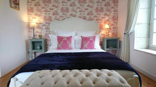 une chambre avec un grand lit avec des oreillers roses dans l'établissement L'Olivier, à Monts-sur-Guesnes