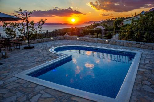 a swimming pool with a sunset in the background at Villa Ursula in Podgora