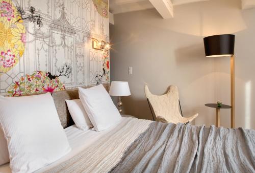 a bedroom with a bed with white sheets and a chair at Hôtel Le Pré Saint Michel in Manosque