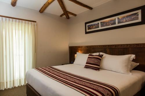 a bedroom with a bed with white sheets and a window at Del Pilar Ollantaytambo in Ollantaytambo