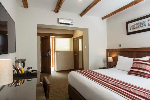 a hotel room with a bed and a television at Del Pilar Ollantaytambo in Ollantaytambo