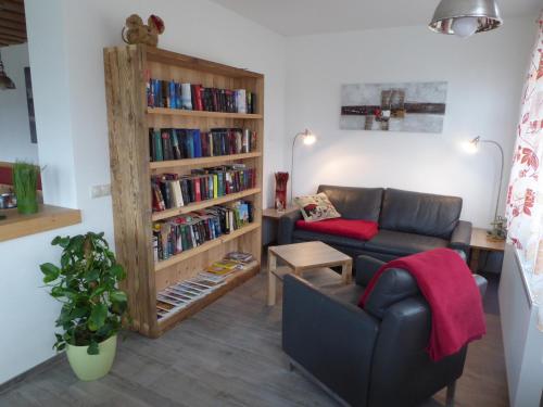 a living room with a couch and a book shelf with books at Pension Haus Edelweiss in Weissensee