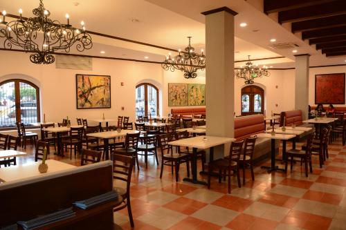 a dining room with tables and chairs and chandeliers at Hotel La Recolección in León