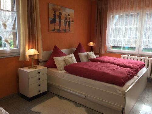 Schlafzimmer mit einem Bett mit roter Bettwäsche und Kissen in der Unterkunft Ferienwohnung Rosi Stoppa in Burg