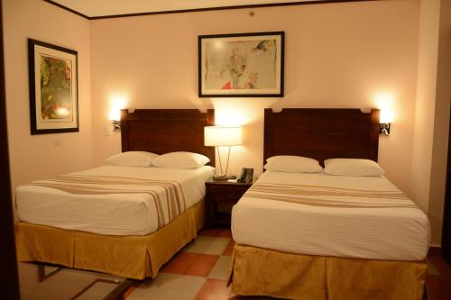 a hotel room with two beds and two lamps at Hotel La Recolección in León