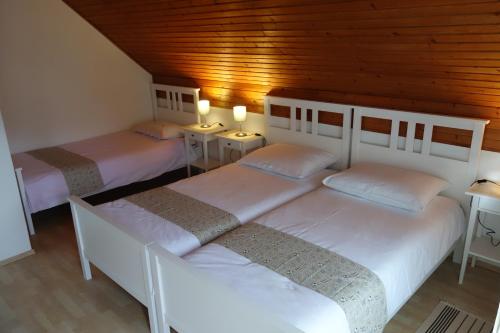 three beds in a room with wooden ceilings at Apartment Makuc in Bovec