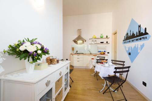 a kitchen with a table with a vase of flowers at Bergamo Sottosopra in Bergamo
