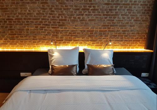 a bed with two pillows and a brick wall at Hotel Goodnight Antwerp in Antwerp
