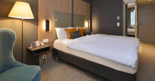 a hotel room with a large bed and a chair at Martin's Louvain-la-Neuve in Louvain-la-Neuve