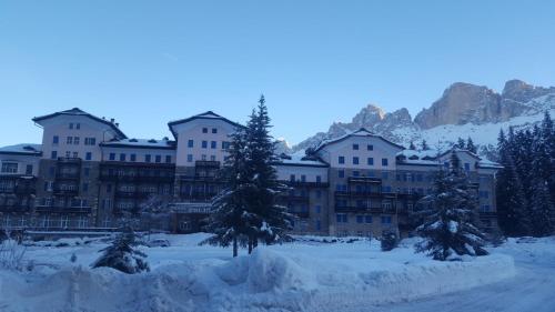 a building covered in snow with trees in the foreground at Residence Grand Hotel Carezza in Nova Levante