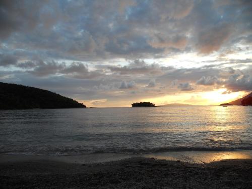 a sunset over a body of water with a beach at Apartmani Maslina Žuljana in Žuljana