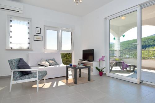 a white living room with a couch and a table at Apartment Andrea in Sveta Marina