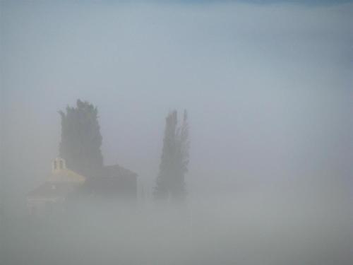 a foggy view of a house in the distance with trees at Agriturismo Le Roghete in Acquapendente