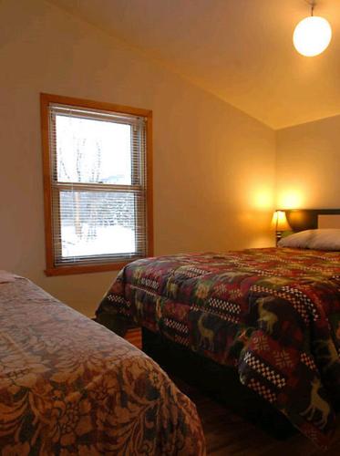 a bedroom with two beds and a window at Le Genevrier in Baie-Saint-Paul
