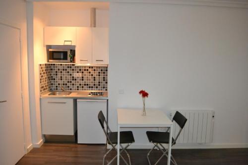 een kleine keuken met een witte tafel en stoelen bij Room Gran Vía Apartments in Madrid