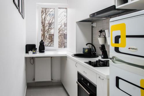 a white kitchen with a sink and a stove at Bike-Friendly Apartment in Timişoara