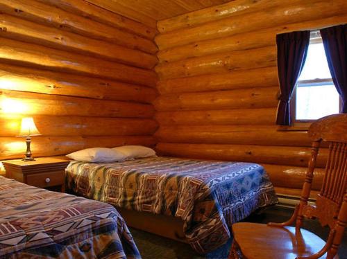 a bedroom with two beds in a log cabin at Le Genevrier in Baie-Saint-Paul