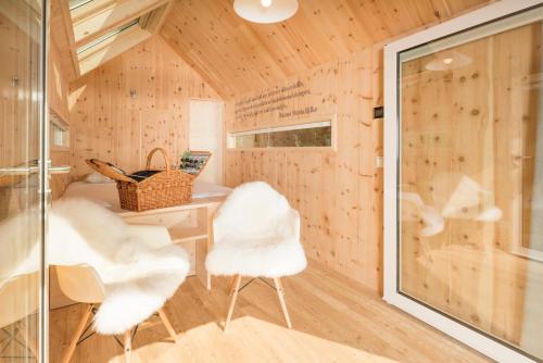 a tiny house with white chairs and a desk at refugium am see in Seeboden