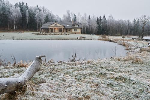 a house with a log in front of a lake at Prūsiškių dvaras in Sumiliszki