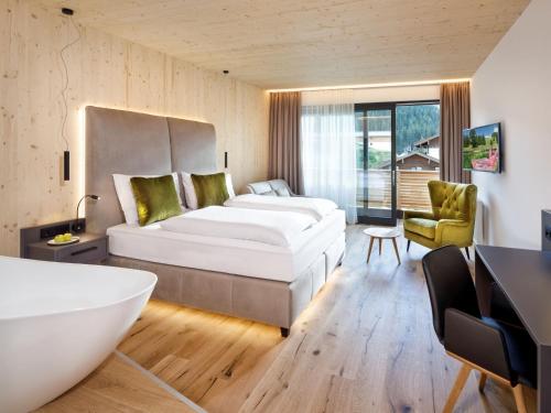 um quarto com uma cama grande e uma banheira em Das KATSCHBERG Superior em Katschberghöhe