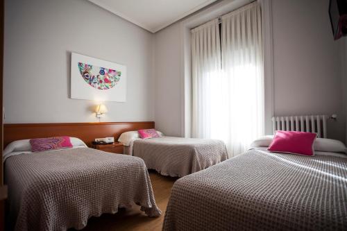 マドリードにあるオスタル サンタ クルスのピンクの枕が付いたベッド2台が備わる客室です。