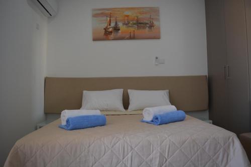 a bed with two blue pillows on top of it at P.L Hermes Studios & Apartments in Larnaka