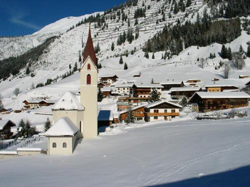 a small town covered in snow with a church at Gasthaus Alpenrose in Gramais