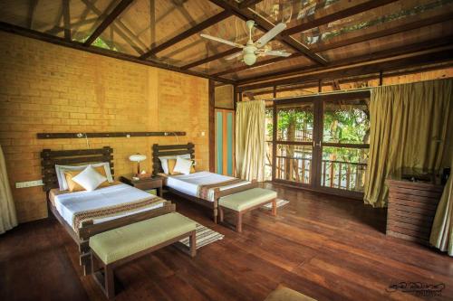 a bedroom with two beds and a ceiling fan at Jungle Village by Thawthisa in Unawatuna